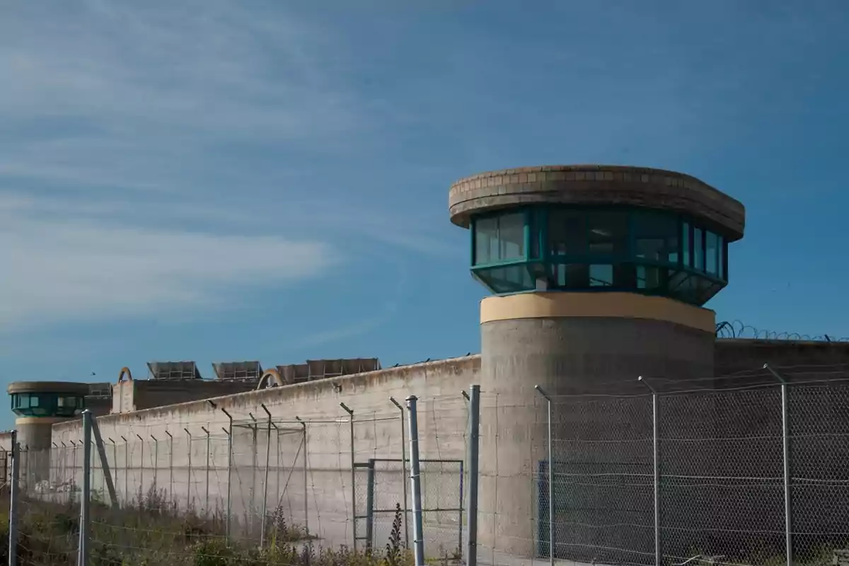 Una prisión con torres de vigilancia y cercas de alambre bajo un cielo despejado. Una prisión con torres de vigilancia y cercas de alambre bajo un cielo despejado.