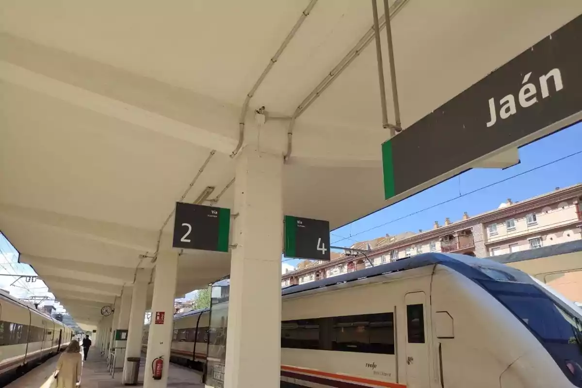 Estación de tren con andenes numerados y un tren en la vía, con un cartel que indica Estación de tren con andenes numerados y un tren en la vía, con un cartel que indica