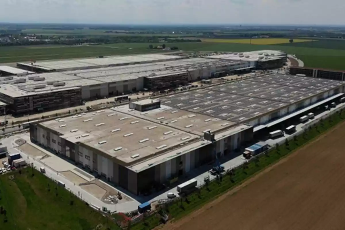 Vista aérea de una gran planta industrial rodeada de campos verdes y caminos.