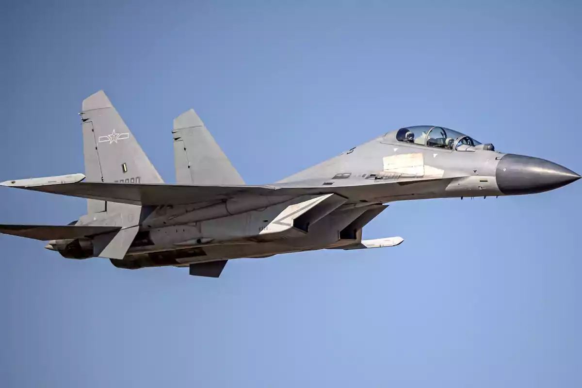 Avión de combate en vuelo con cielo despejado de fondo.