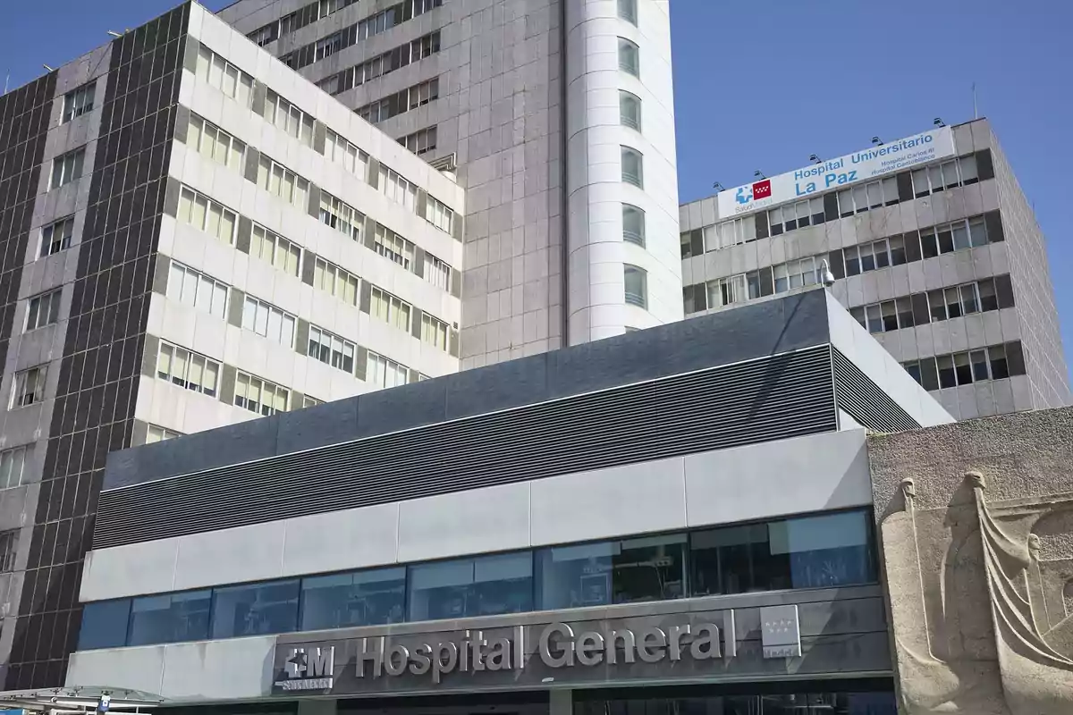 Edificio moderno de hospital con fachada de vidrio y concreto bajo un cielo despejado.