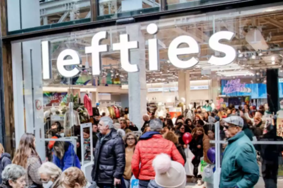 Exterior de una tienda de Lefties con el letrero de grandes dimensiones en la parte superior de las puertas de entrada y varias personas paseando