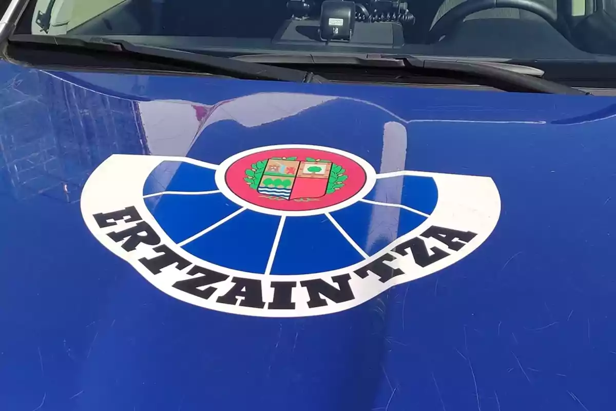 Emblema de la Ertzaintza en el capó de un vehículo policial azul.