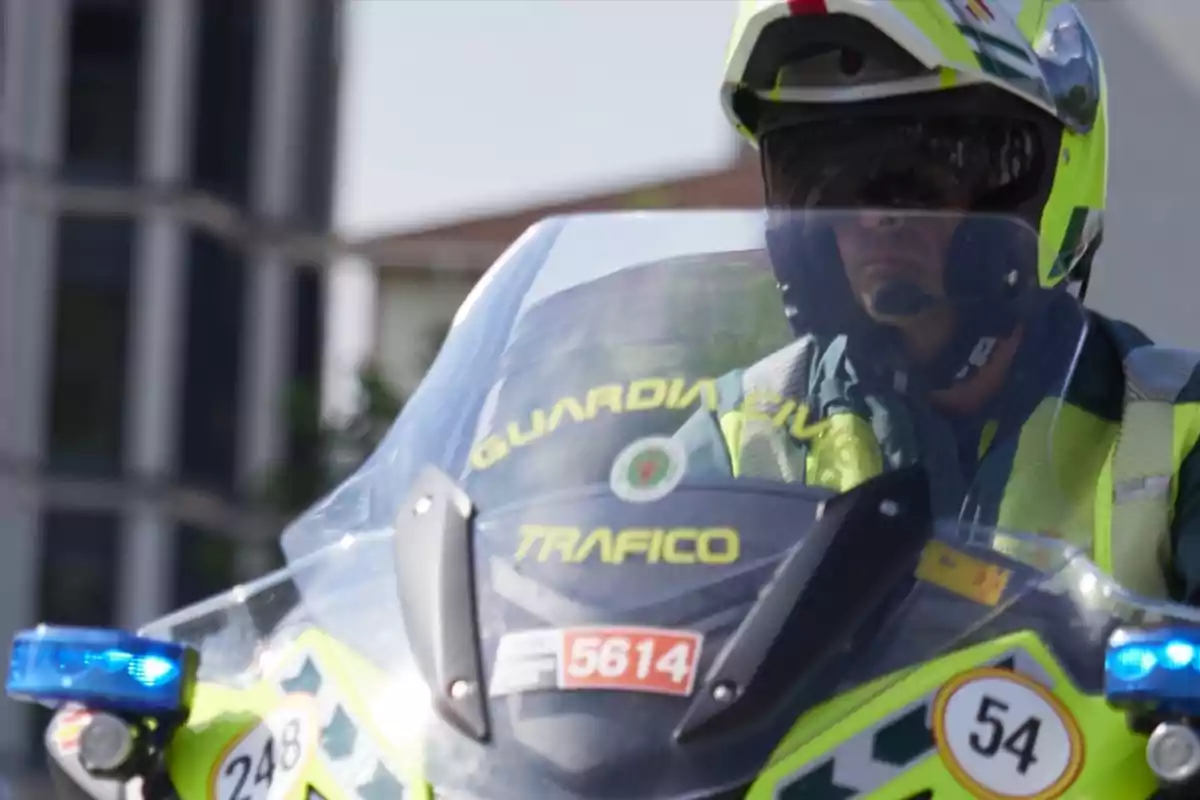 Un agente de tráfico en motocicleta con uniforme y casco de la Guardia Civil.