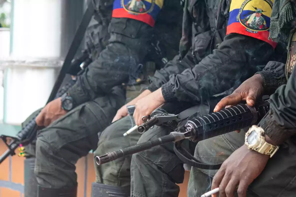 Tres personas con uniformes militares y armas, con parches de la bandera de Ecuador en los brazos.