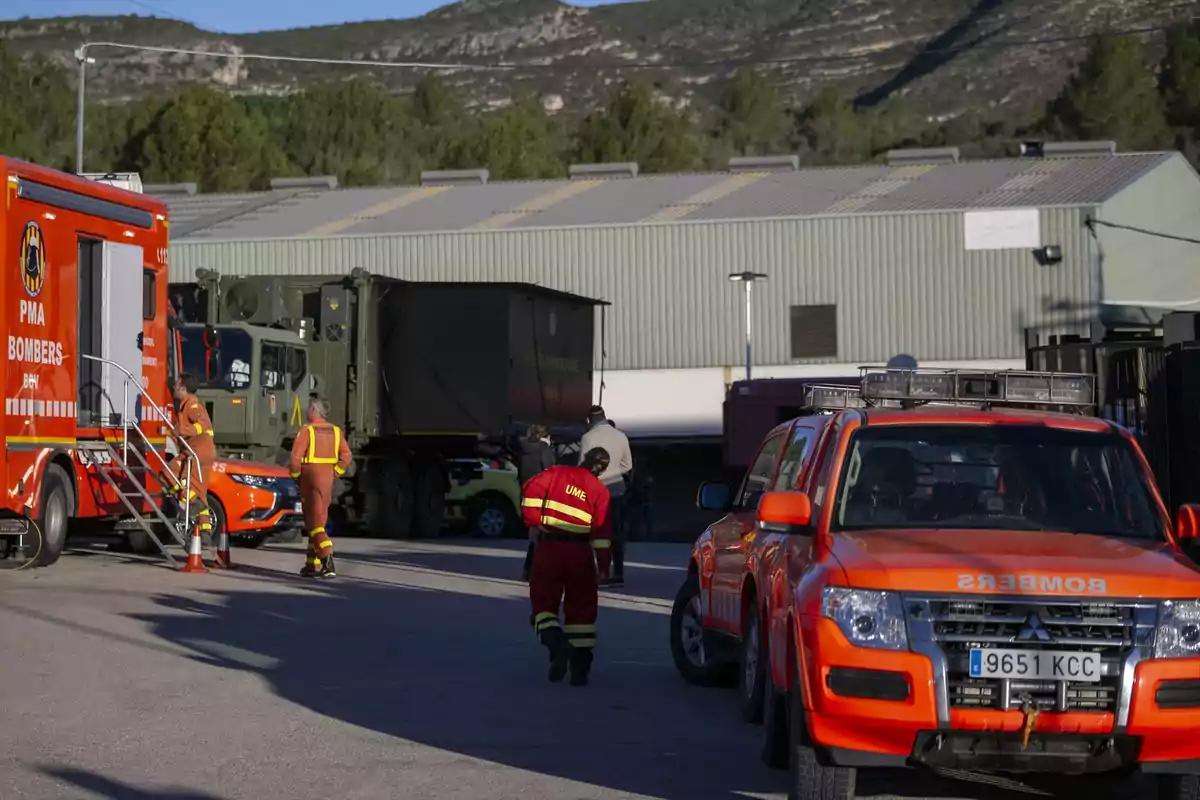 Un grupo de bomberos y personal de emergencia se encuentra en una base con vehículos de rescate y camiones en un entorno montañoso.