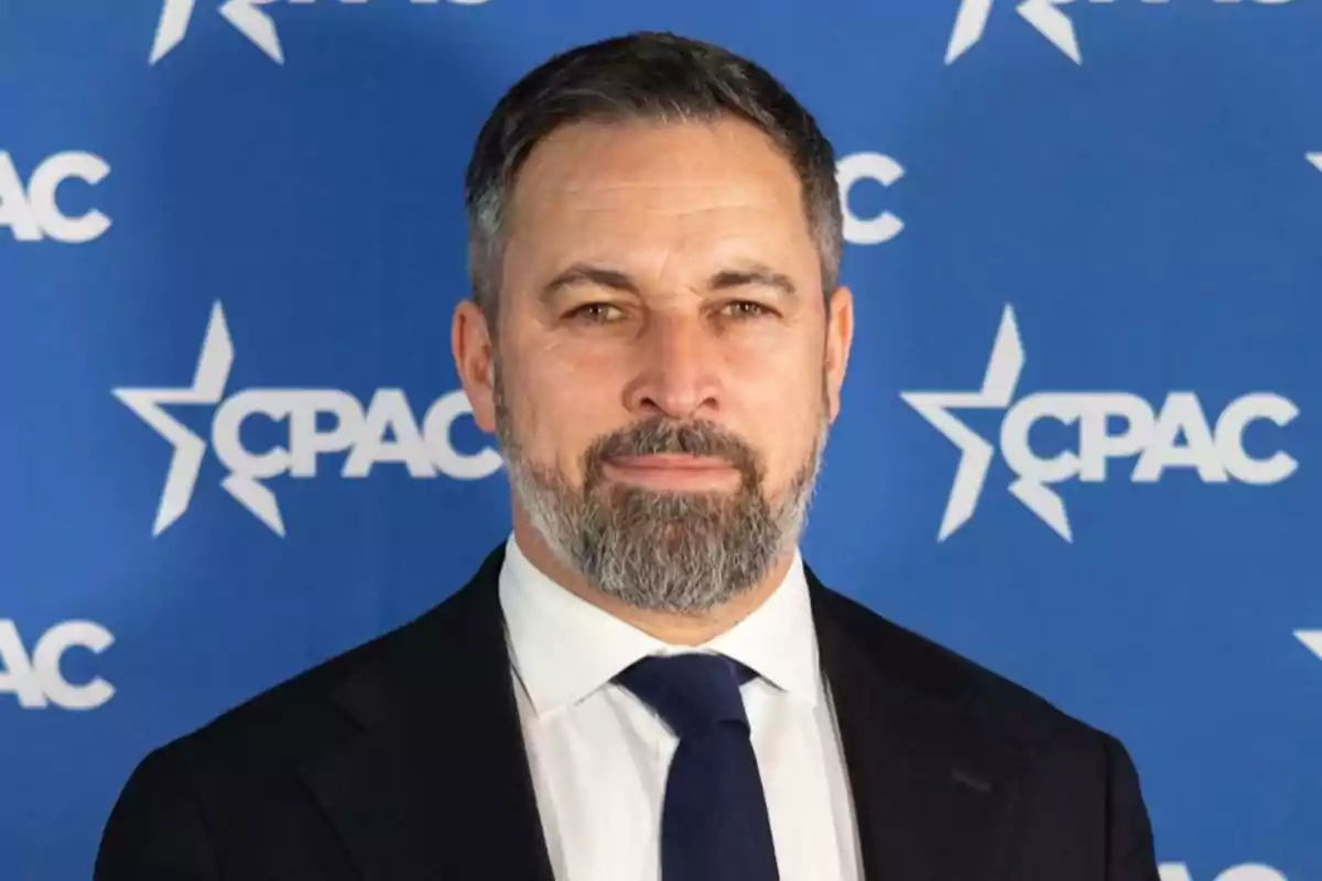 A man with a beard and suit in front of a blue background with the CPAC logo.