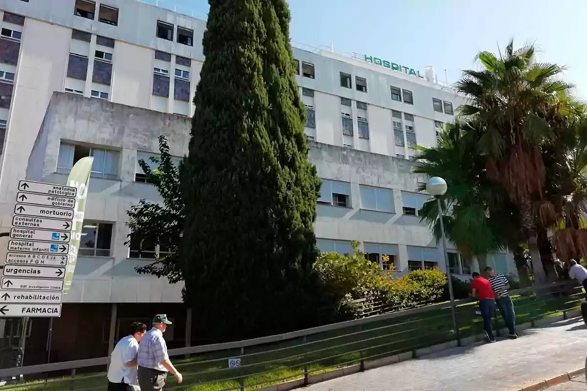 Edificio de hospital con árboles y personas caminando en la acera. Edificio de hospital con árboles y personas caminando en la acera.