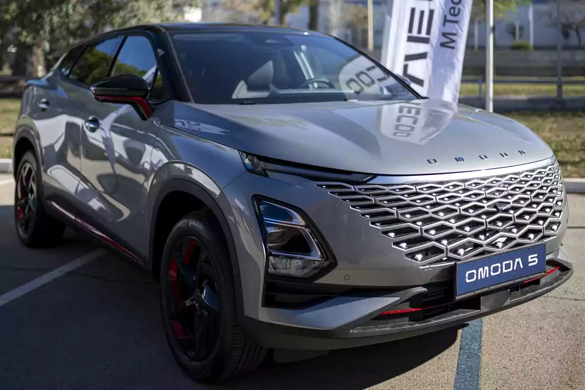 Un automóvil Omoda 5 gris estacionado en un área al aire libre, con un diseño moderno y una parrilla frontal distintiva.