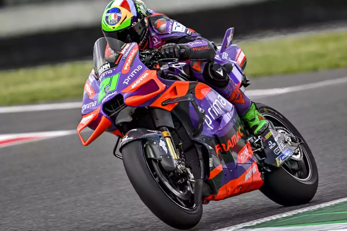 Un motociclista compitiendo en una carrera, montando una moto de carreras con colores vibrantes y patrocinadores visibles en el carenado.