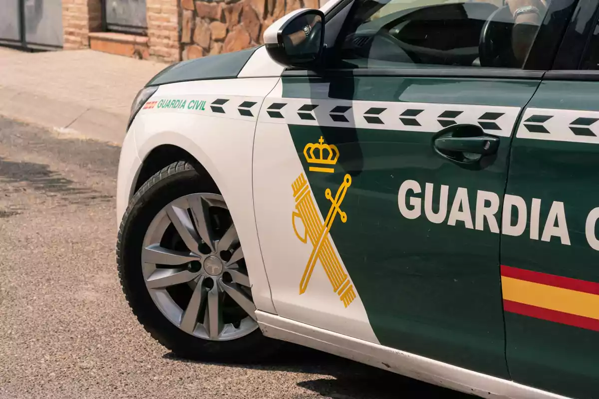 Un coche de la Guardia Civil estacionado en una calle con el emblema y los colores característicos en el lateral.