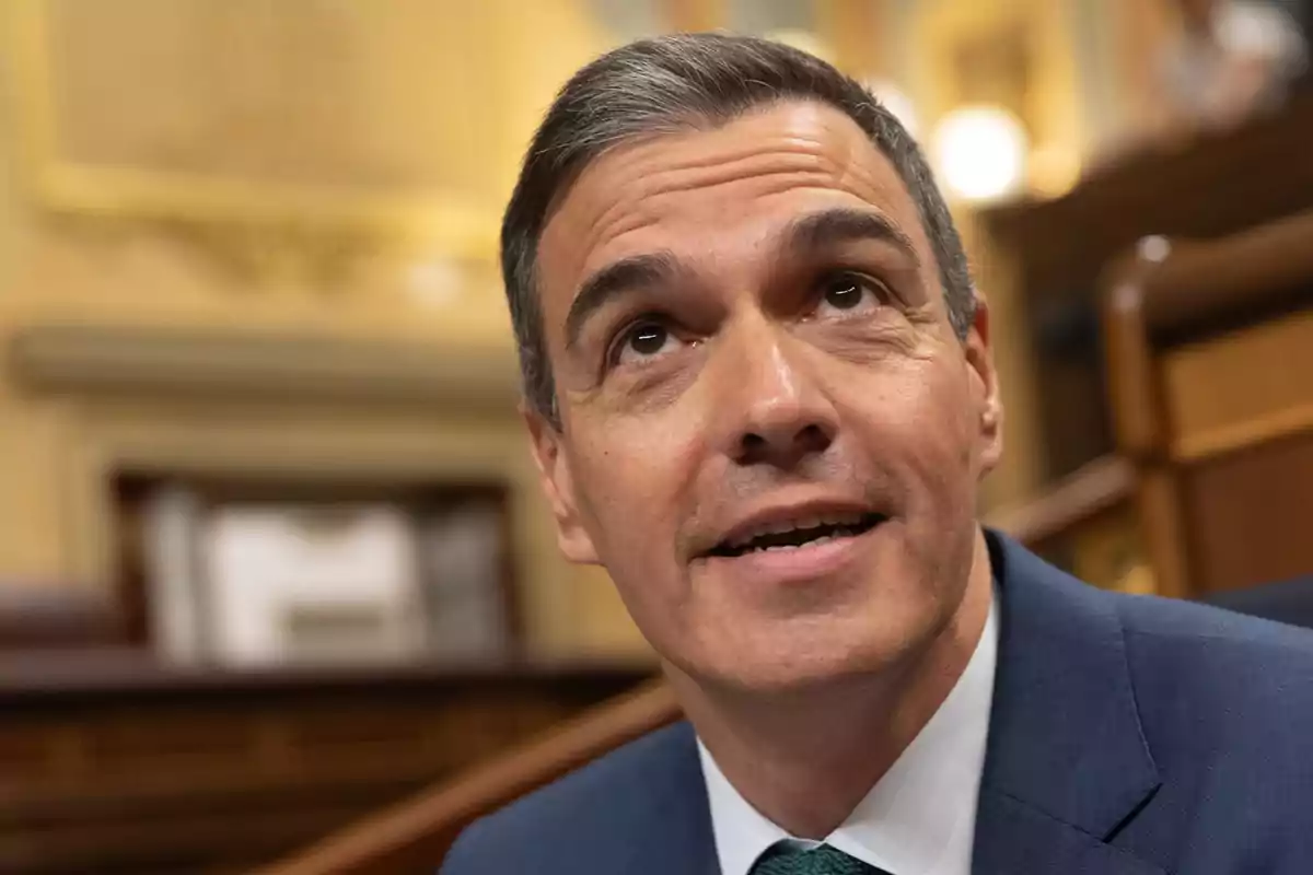 Hombre con traje azul y corbata verde en un entorno formal.