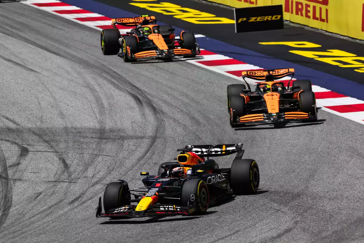 Tres autos de Fórmula 1 compitiendo en una pista de carreras con publicidad de Pirelli en el fondo.