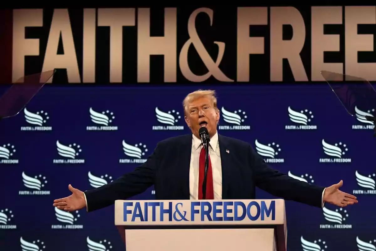 Un hombre hablando en un podio con las palabras "FAITH & FREEDOM" en el fondo.