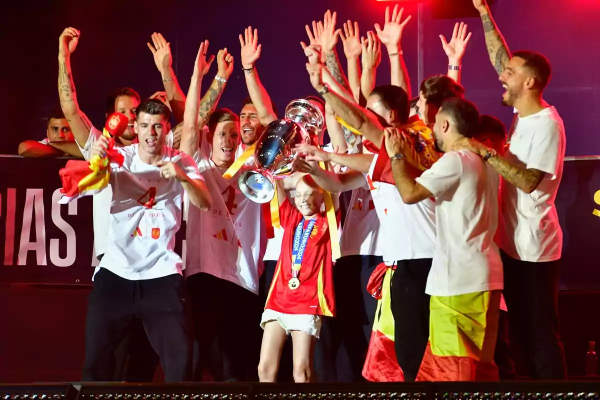 Un grupo de personas celebrando con un trofeo y banderas de España.