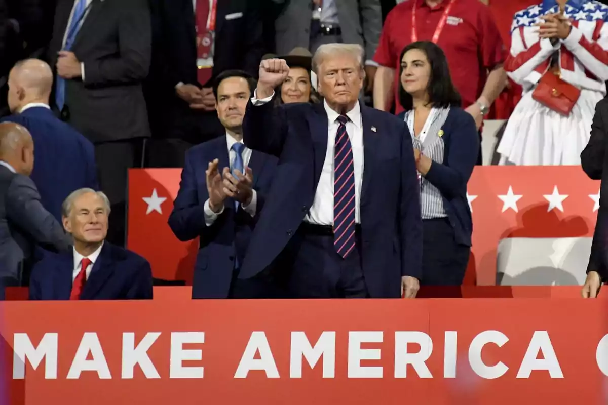 Un grupo de personas en un evento con un cartel rojo que dice "MAKE AMERICA".