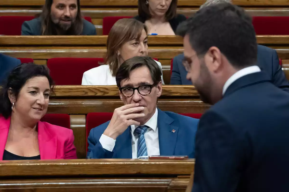 Personas sentadas en un parlamento, algunas conversando entre sí.