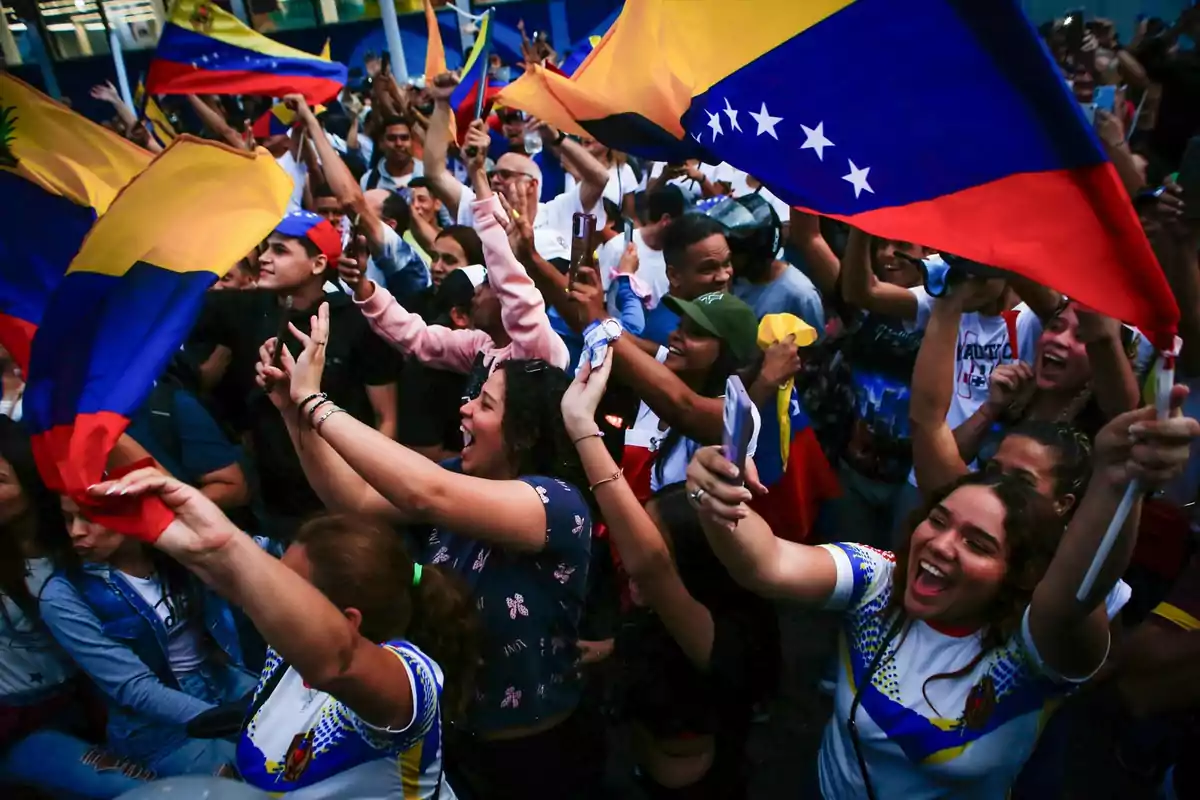 Personas celebrando con banderas de Venezuela en un evento al aire libre.