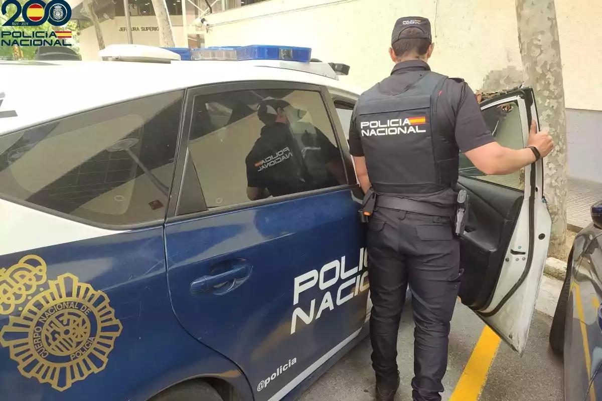 Un agente de la Policía Nacional de España junto a un coche patrulla