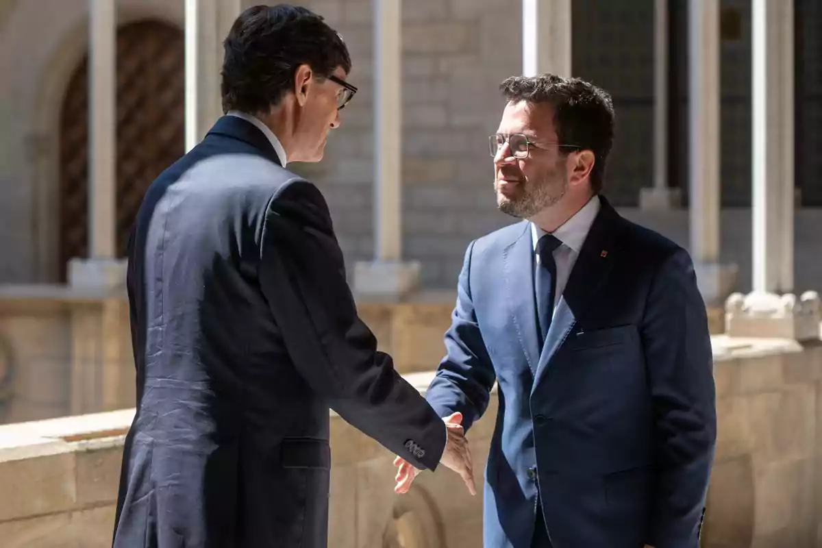 Dos hombres de traje dándose la mano en un entorno formal.