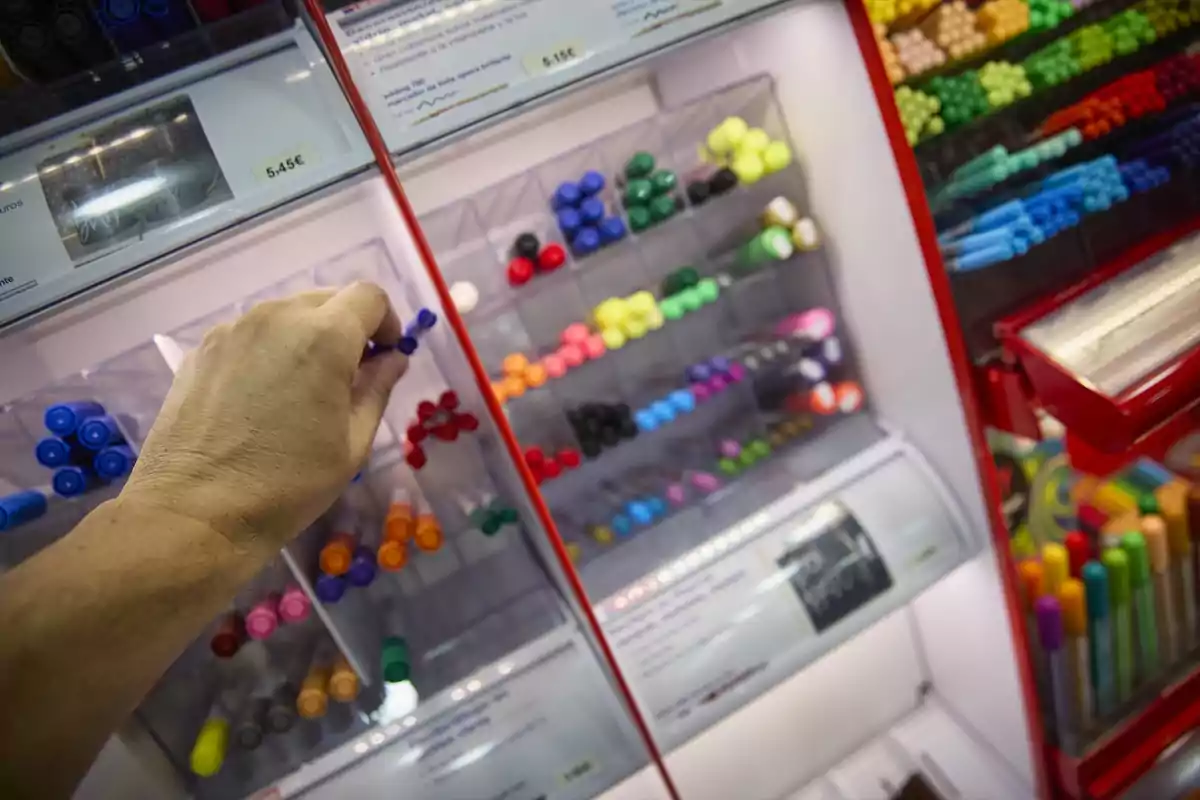 Persona eligiendo rotuladores de colores en una tienda de artículos de papelería.