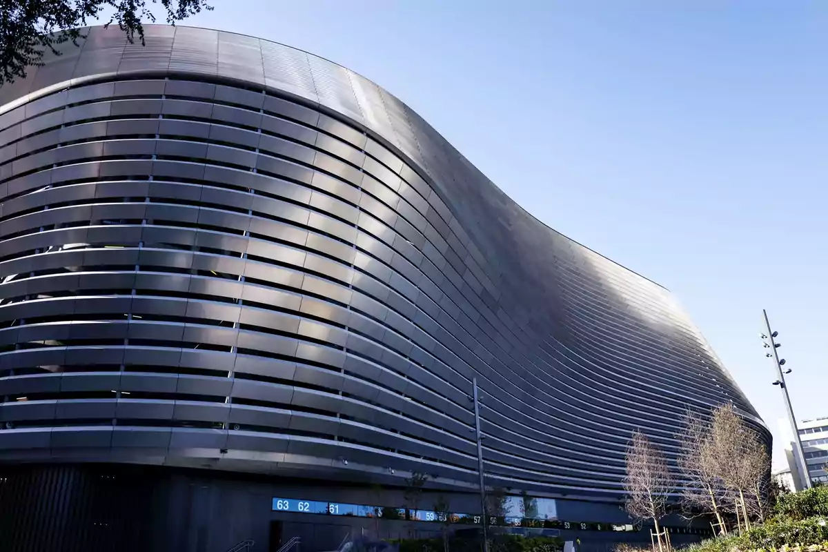 Edificio moderno con diseño curvo y fachada de metal en un día soleado.