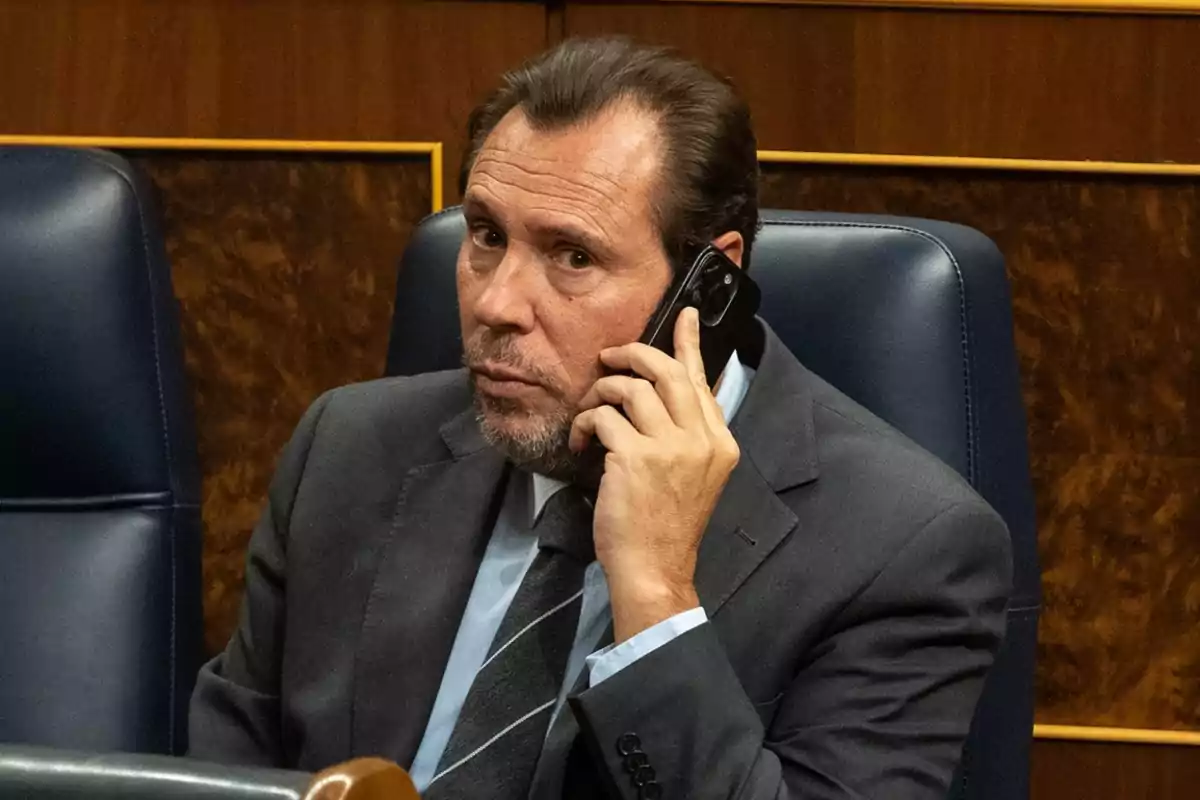 Hombre de traje hablando por teléfono móvil en una sala de reuniones.