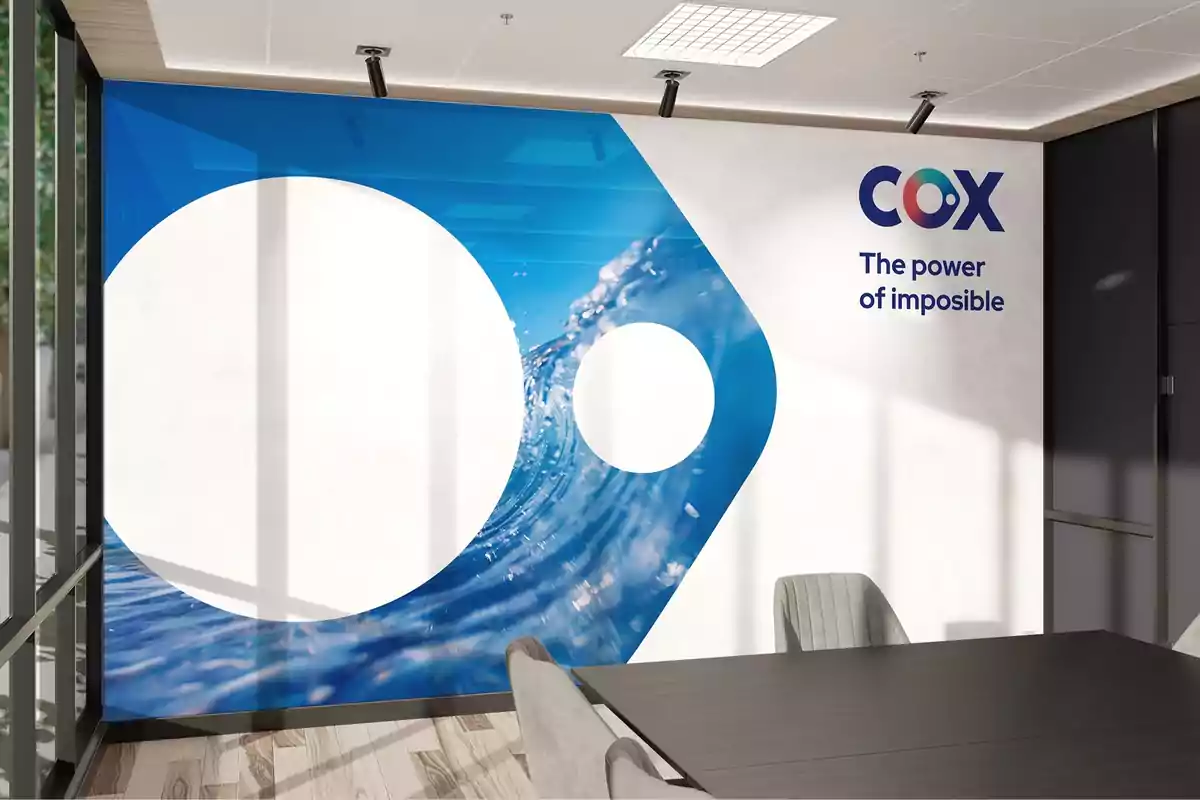 Sala de reuniones moderna con una pared decorada con un diseño azul y blanco y el texto "COX The power of imposible".