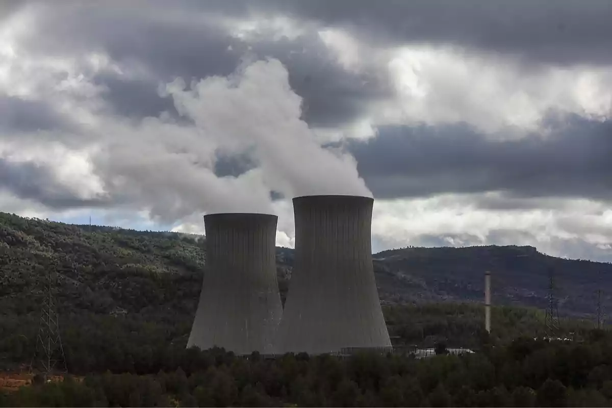 Torres de enfriamiento de una planta industrial emitiendo vapor en un paisaje montañoso con cielo nublado. Torres de enfriamiento de una planta industrial emitiendo vapor en un paisaje montañoso con cielo nublado.