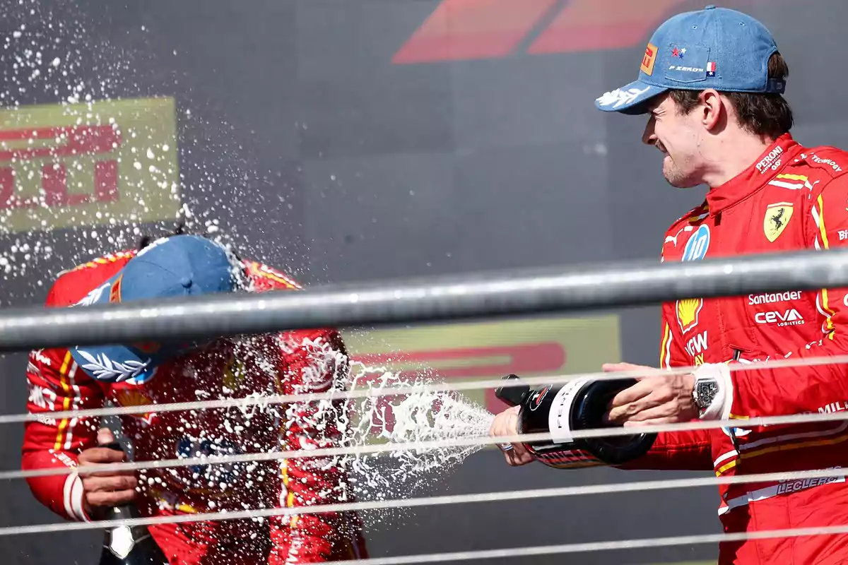 Dos pilotos de Ferrari celebran en el podio con champán.