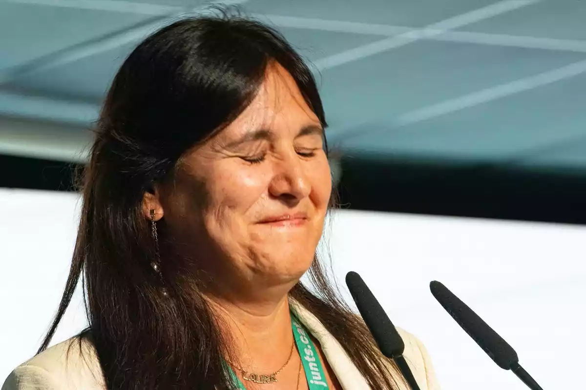 Una persona con el cabello oscuro y ojos cerrados frente a un micrófono.