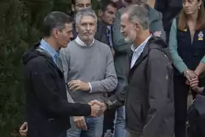 Dos hombres se dan la mano mientras otras personas observan en el fondo.