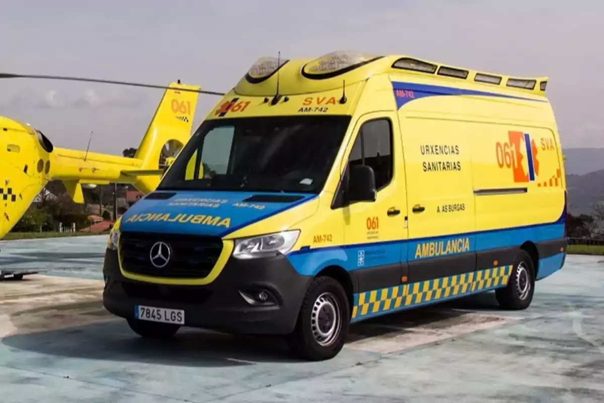 Una ambulancia amarilla y azul está estacionada en un helipuerto junto a un helicóptero amarillo, ambos con el número 061 visible. Una ambulancia amarilla y azul está estacionada en un helipuerto junto a un helicóptero amarillo, ambos con el número 061 visible.