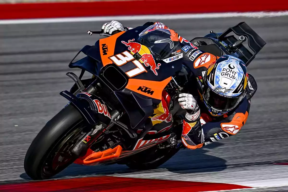 Piloto de motociclismo en una curva montando una moto KTM con diseño de Red Bull en un circuito de carreras.