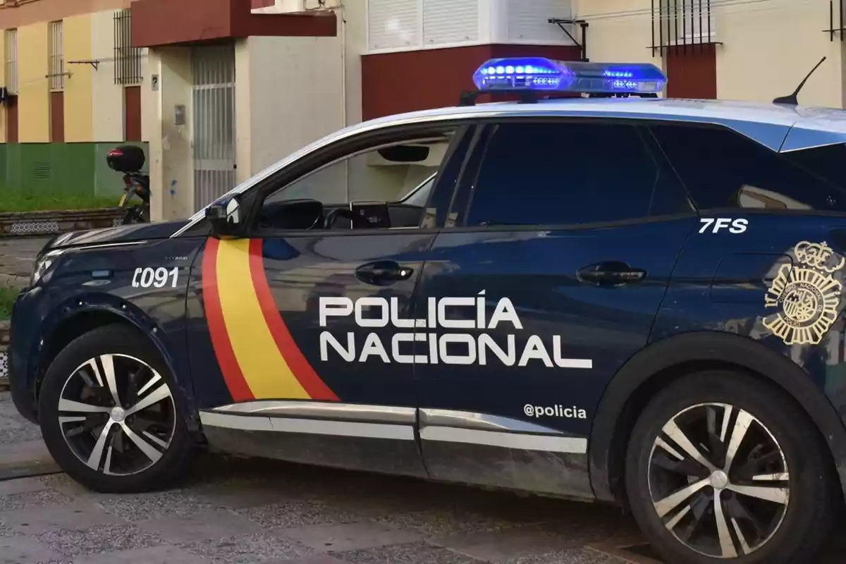 Un coche de la Policía Nacional de España estacionado frente a un edificio residencial.