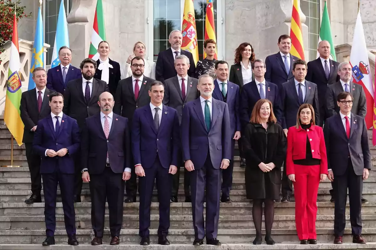 Grupo de personas posando en las escaleras de un edificio oficial con varias banderas autonómicas de fondo Grupo de personas posando en las escaleras de un edificio oficial con varias banderas autonómicas de fondo