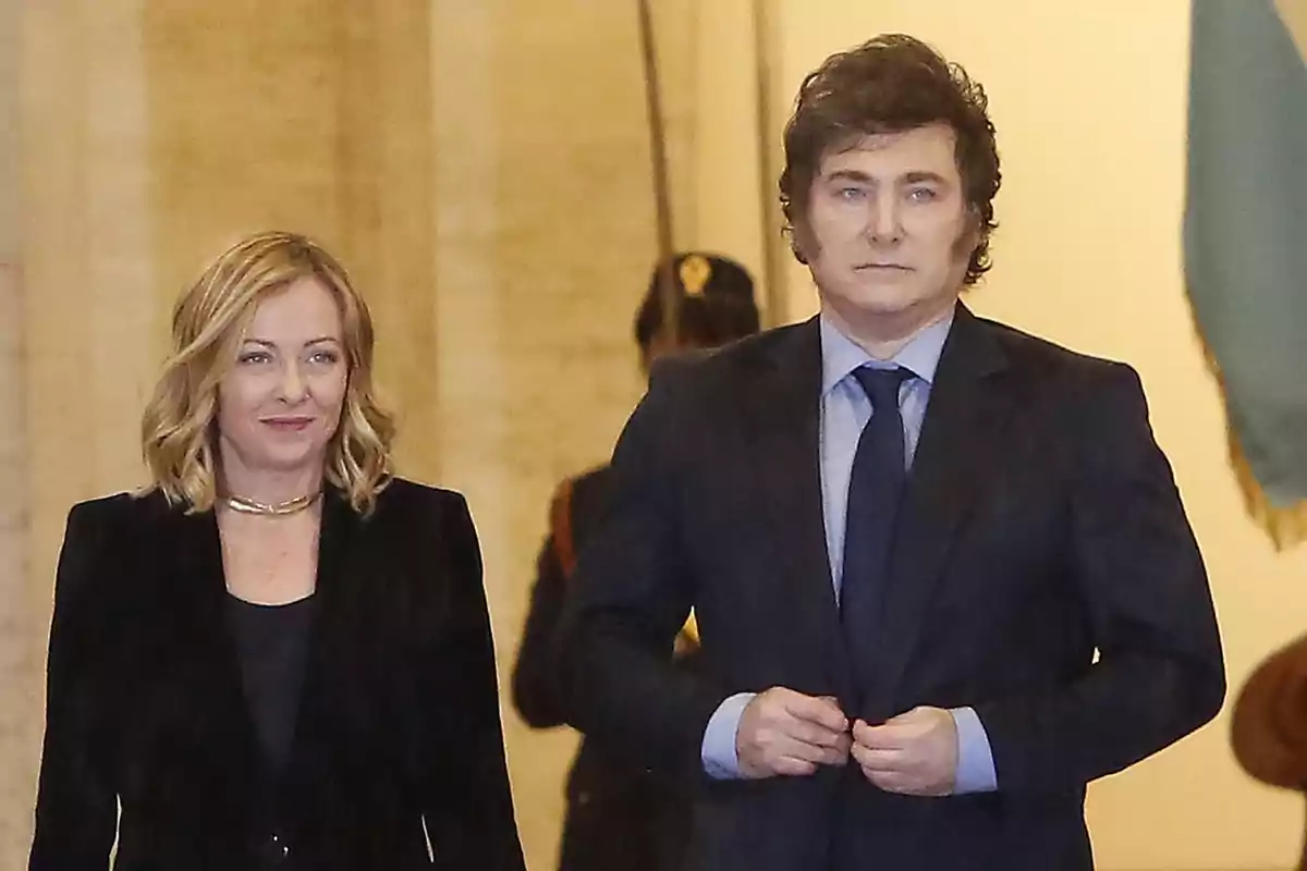 Dos personas vestidas de manera formal caminan juntas en un entorno elegante y bien iluminado