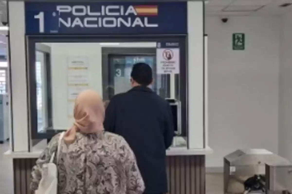 Two people are standing in front of a National Police window in an office.