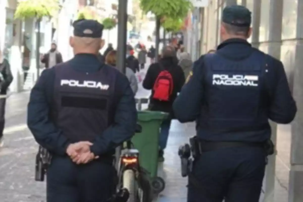 Dos policías caminando por una calle concurrida.