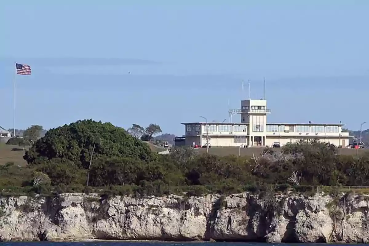 Building next to a cliff with a flag waving in the background.