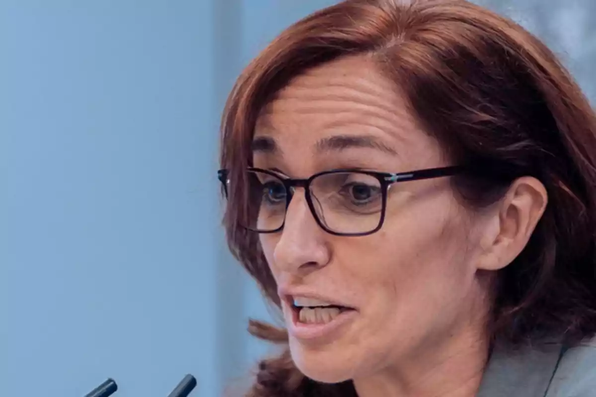 Una persona con gafas hablando en un micrófono. Una persona con gafas hablando en un micrófono.