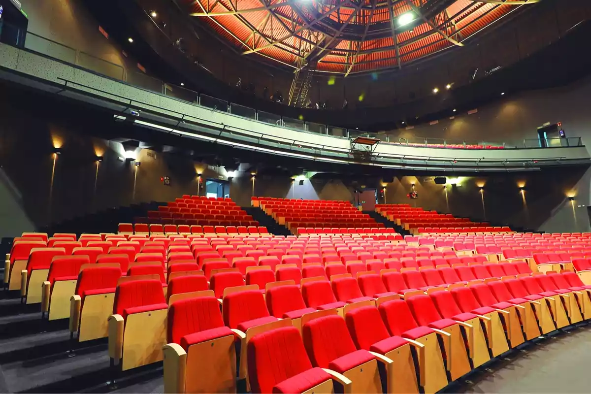 An empty auditorium with rows of red seats and an illuminated vaulted ceiling.