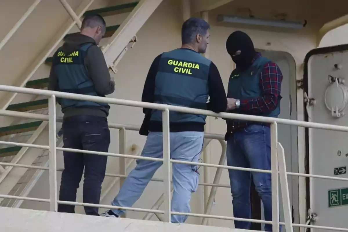 Tres agentes de la Guardia Civil conversan en la cubierta de un barco, uno de ellos lleva pasamontañas. Tres agentes de la Guardia Civil conversan en la cubierta de un barco, uno de ellos lleva pasamontañas.