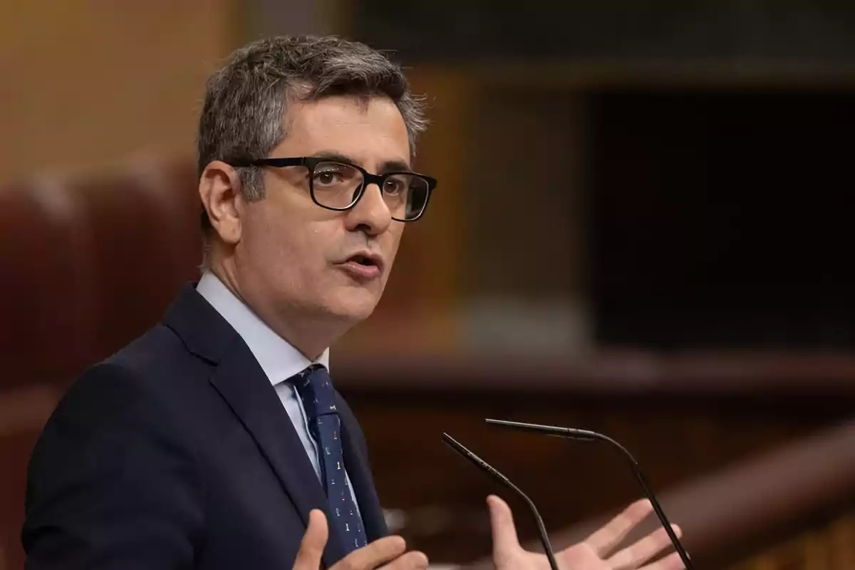 Un hombre con gafas y traje hablando en un podio.