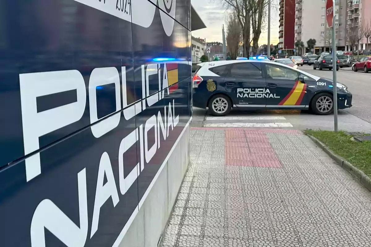 Un coche de la Policía Nacional estacionado junto a un edificio con el mismo logotipo en la fachada.