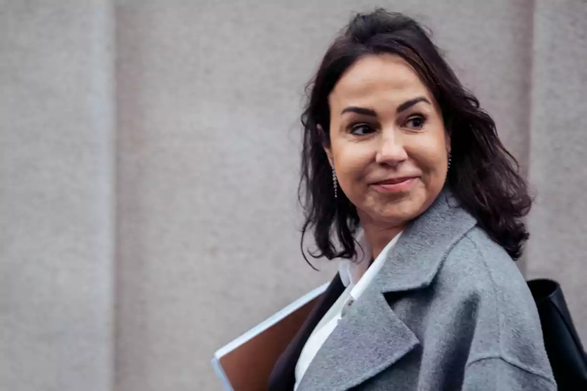 Mujer con abrigo gris sonriendo mientras mira hacia un lado. Mujer con abrigo gris sonriendo mientras mira hacia un lado.