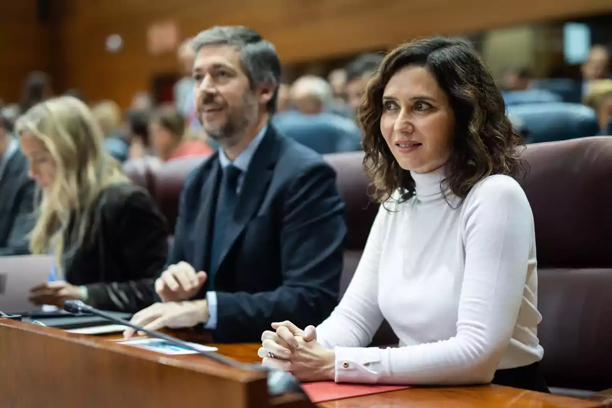 Personas sentadas en una sala de conferencias, prestando atención a un evento.