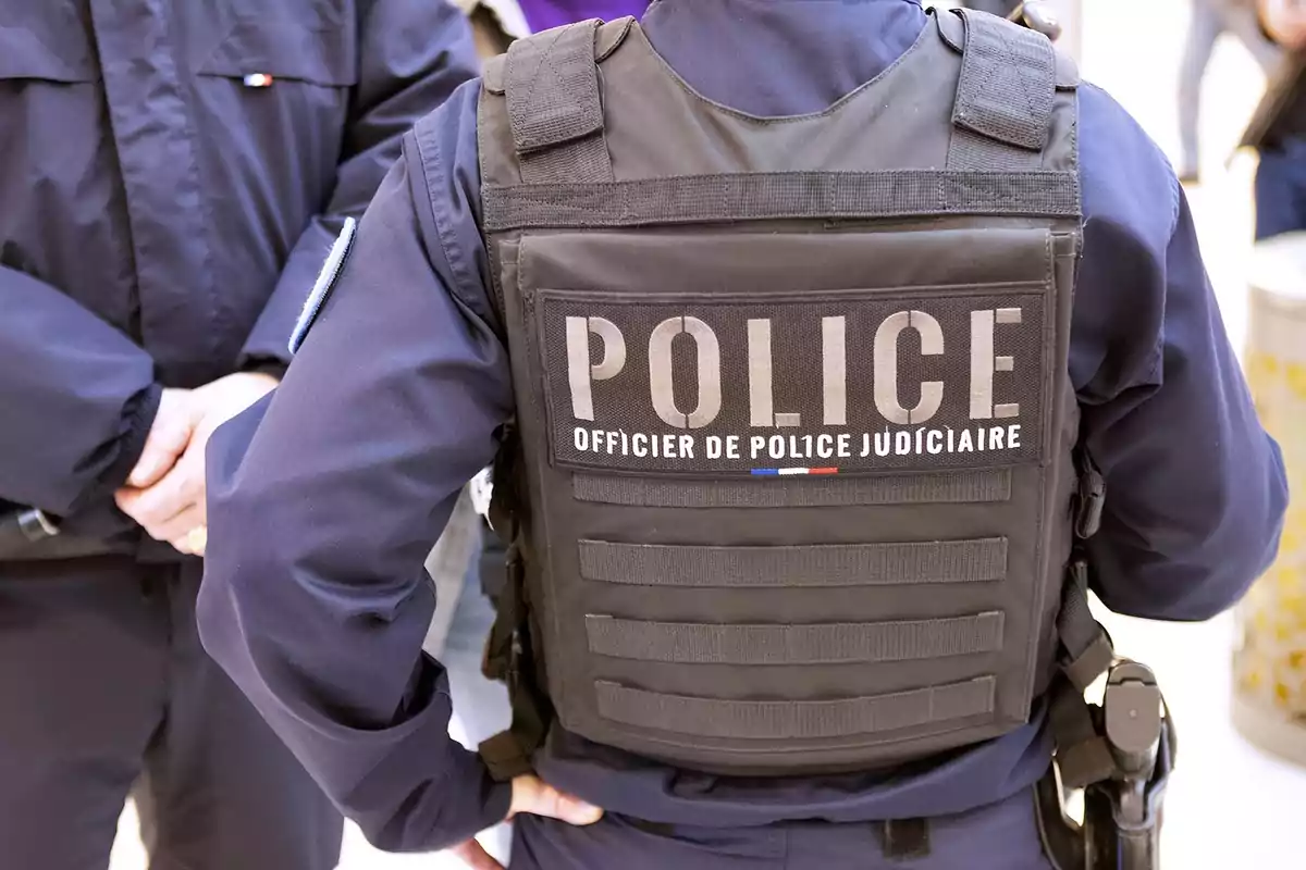 Agente de policía judicial con chaleco antibalas de espaldas en un entorno urbano