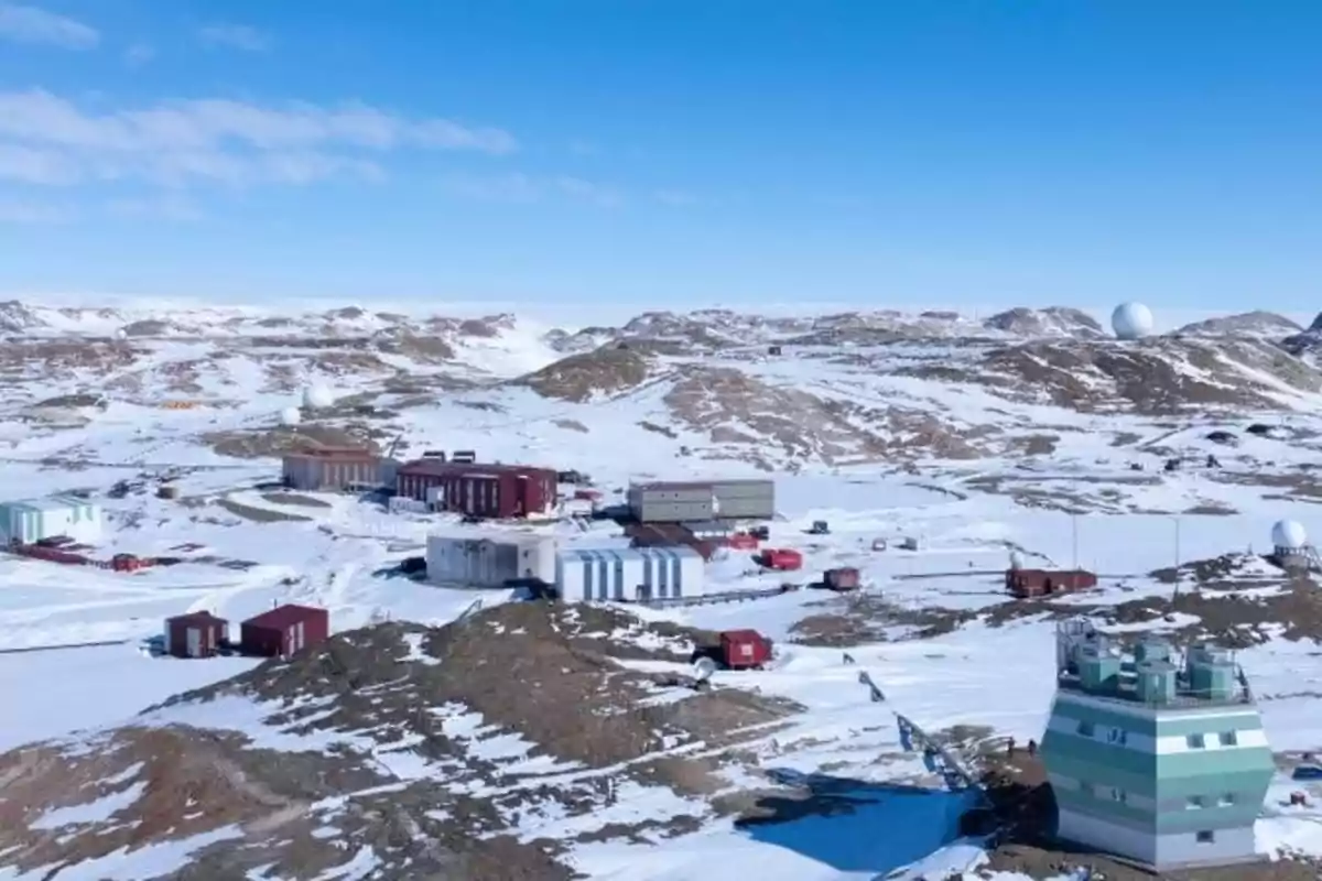 Base de investigación en un paisaje nevado con varias estructuras y colinas al fondo.