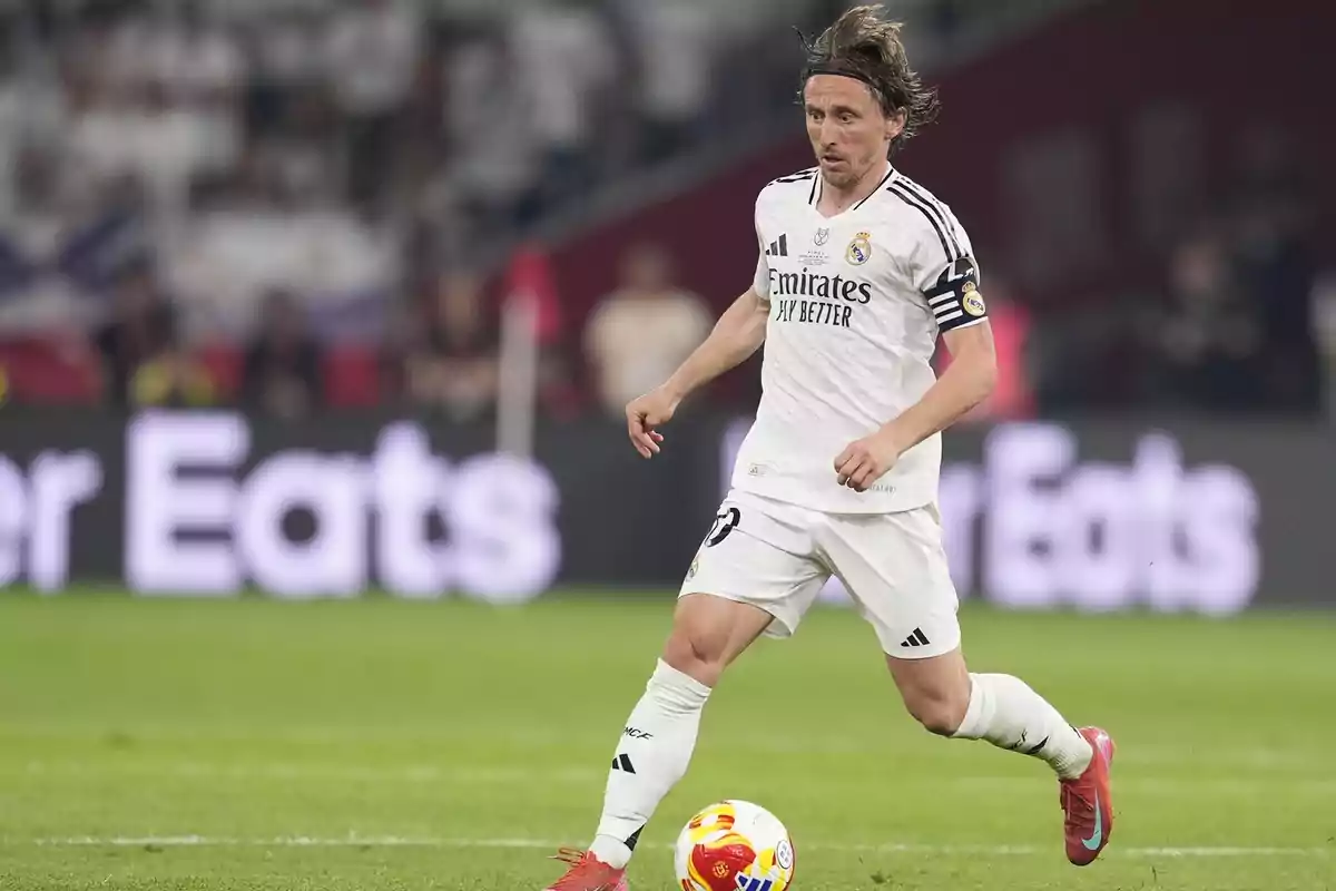 Un jugador de fútbol con uniforme blanco y negro corre en el campo durante un partido. Un jugador de fútbol con uniforme blanco y negro corre en el campo durante un partido.